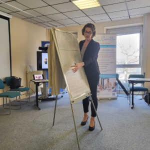 Une femme devant un paperboard montrant des éléments inscrits dessus